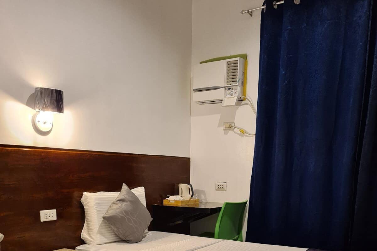Une chambre d’hôtel avec deux lits, un bureau, une chaise, une machine à café et un appareil de climatisation.