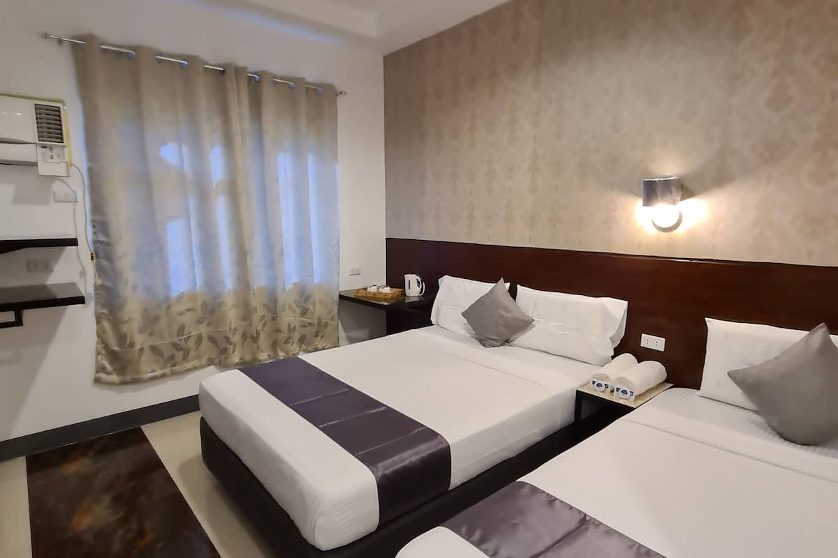 Une chambre d’hôtel avec deux lits, une table de chevet, une lampe et une fenêtre avec des rideaux.