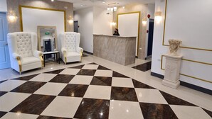 A lobby with a checkered floor, two white armchairs, a reception desk, and a ceiling fan. - My Stay Hotel - Near SM Mall - 1 min walk (Butuan)