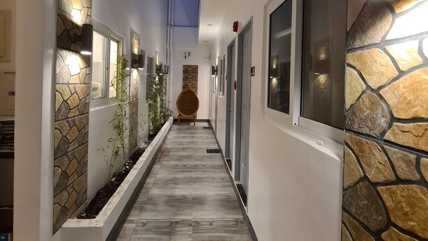 A corridor with stone wall accents, recessed lighting, and a central seating area. - My Stay Hotel - Near SM Mall - 1 min walk (Butuan)