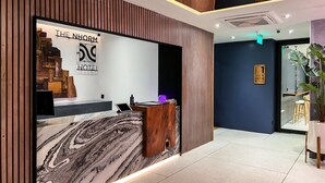 A reception desk with a marble countertop, a wooden panel wall, and a sign reading "The NHORM HOTEL". - The Nhorm Hotel Ratchada (Bangkok)