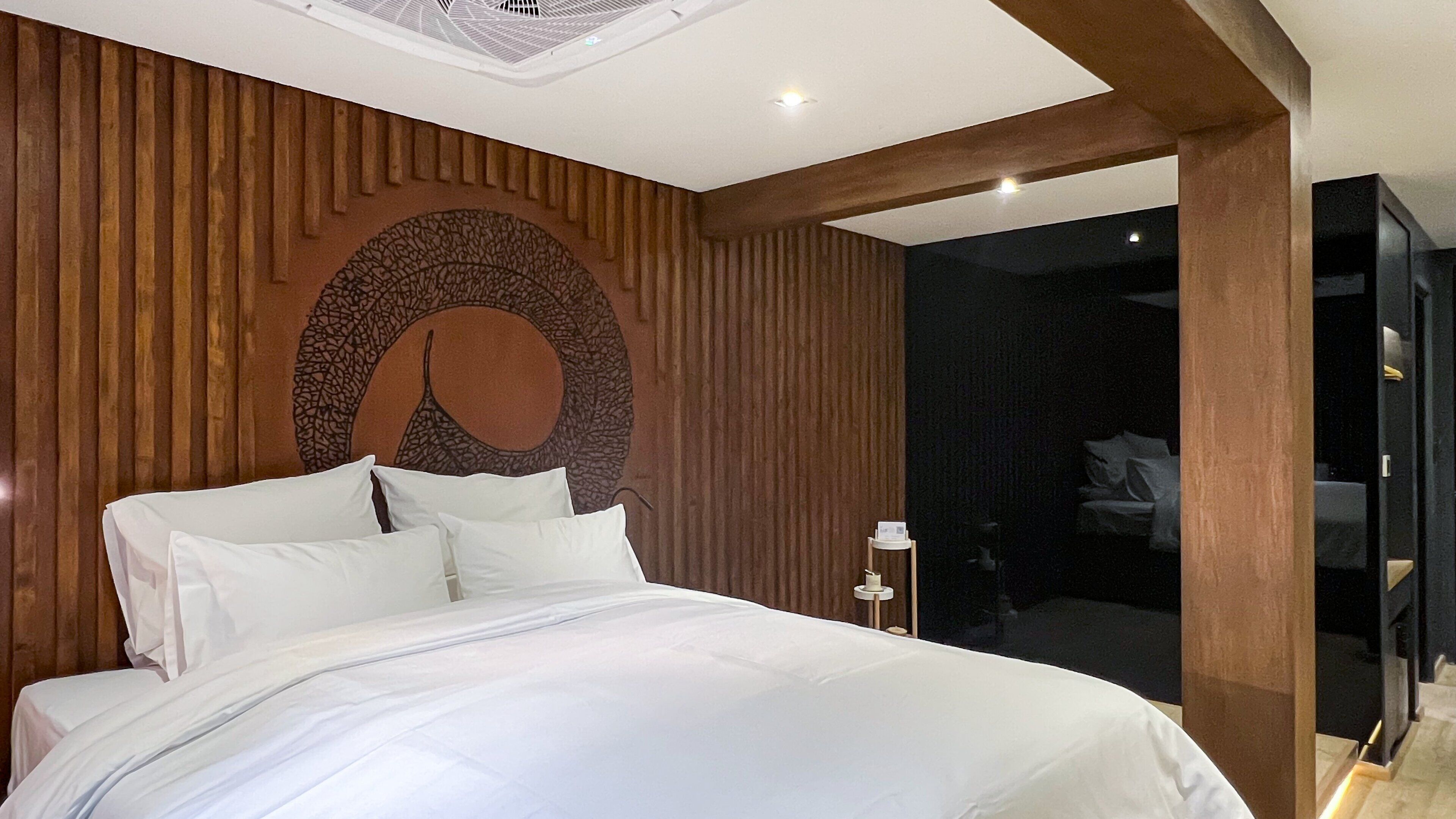 Un dormitorio moderno con una cama grande, paneles de madera en las paredes y un diseño circular único en la cabecera.