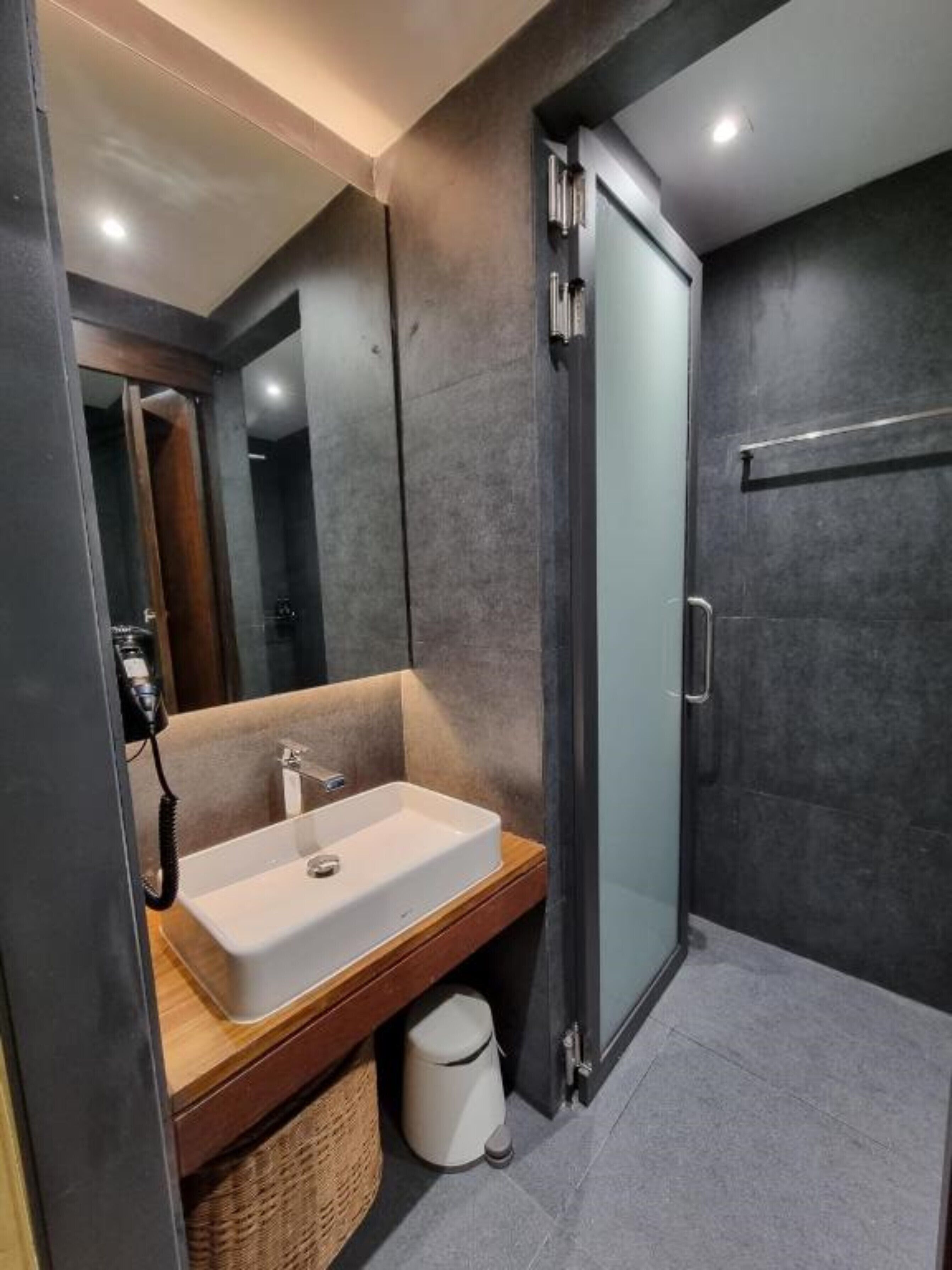 Une salle de bain moderne avec un grand miroir, un lavabo blanc et une douche à parois de verre.