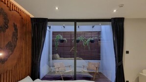 A bedroom with a large bed, a sliding glass door leading to a balcony with two chairs and potted plants. - The Nhorm Hotel Ratchada (Bangkok)