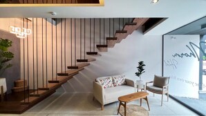 A modern interior with a staircase, a sofa, a coffee table, and a chair. - The Nhorm Hotel Ratchada (Bangkok)