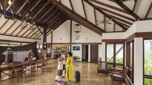 Eine geräumige Lobby mit hoher Decke, Holzbalken, einem gemusterten Fliesenboden und einem Empfangstresen.