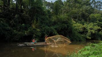 A river with a wooden dock and a person casting a fishing net.