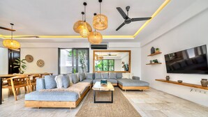 A modern living room with a sectional sofa, a coffee table, and a TV mounted on the wall.