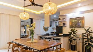 A modern kitchen with a dining area, featuring a wooden table, chairs, and pendant lights.