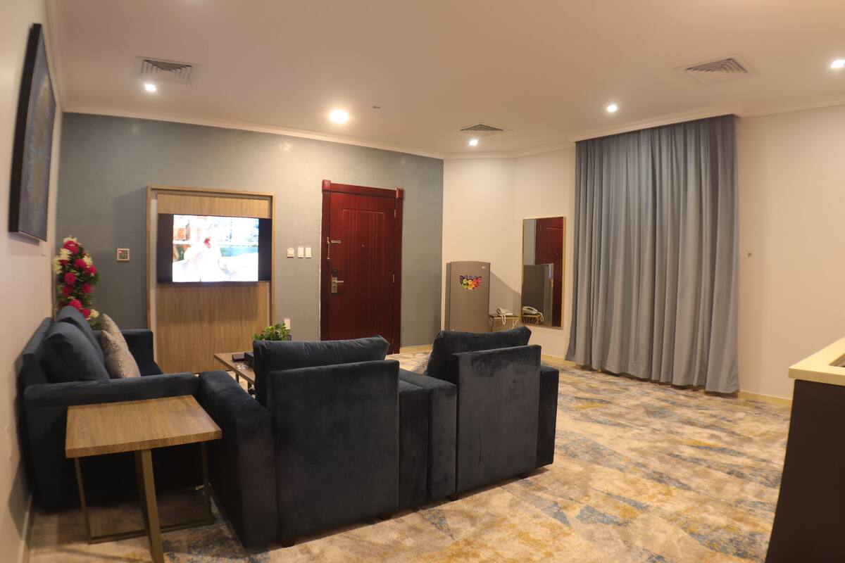 A living room with a sofa, a coffee table, a TV, and a door.