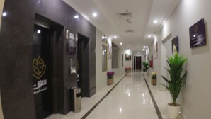 A hotel corridor with a reception desk, a potted plant, and a wall-mounted sign.