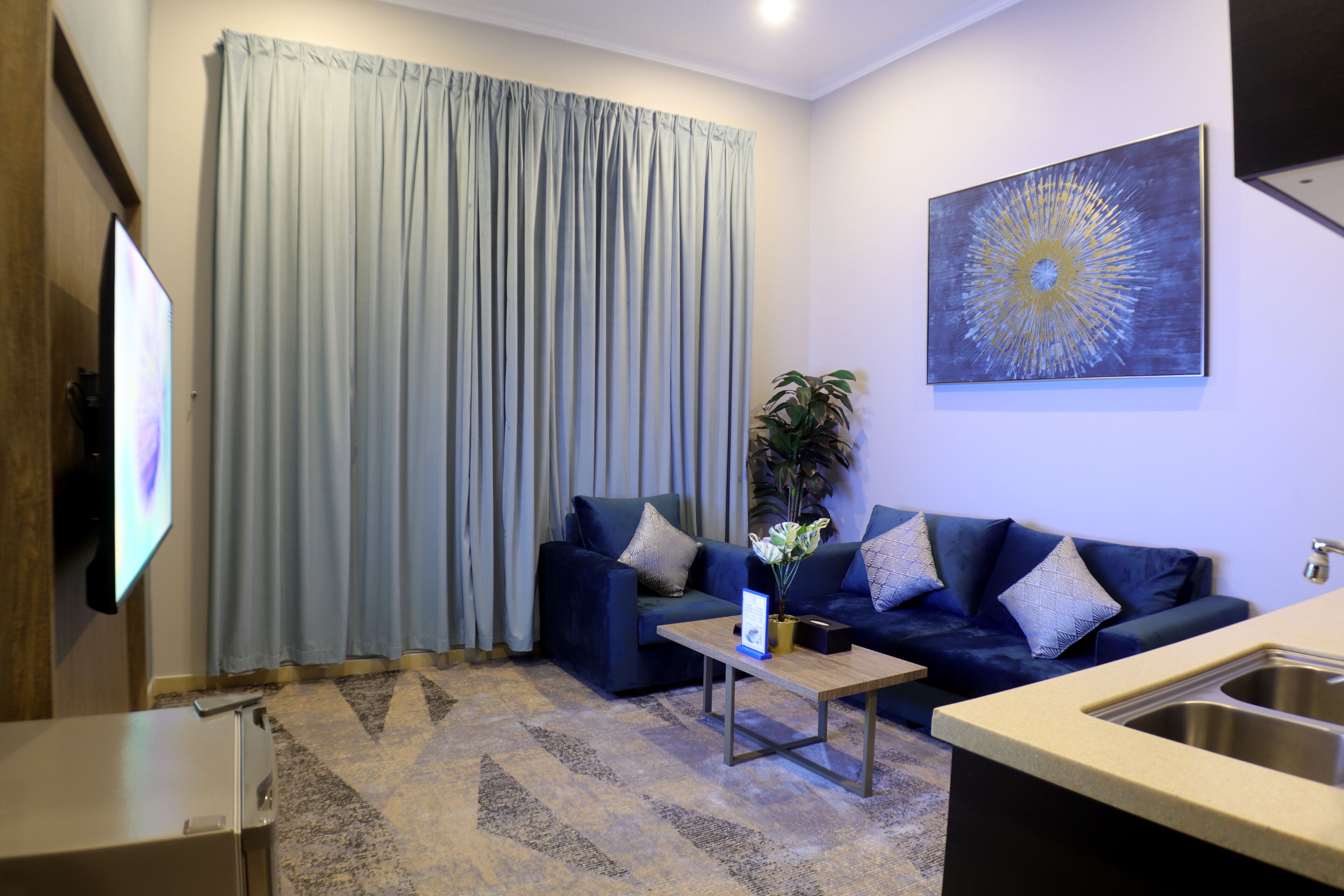 Un salon moderne avec un canapé bleu foncé, une table basse et un grand tableau accroché au mur.