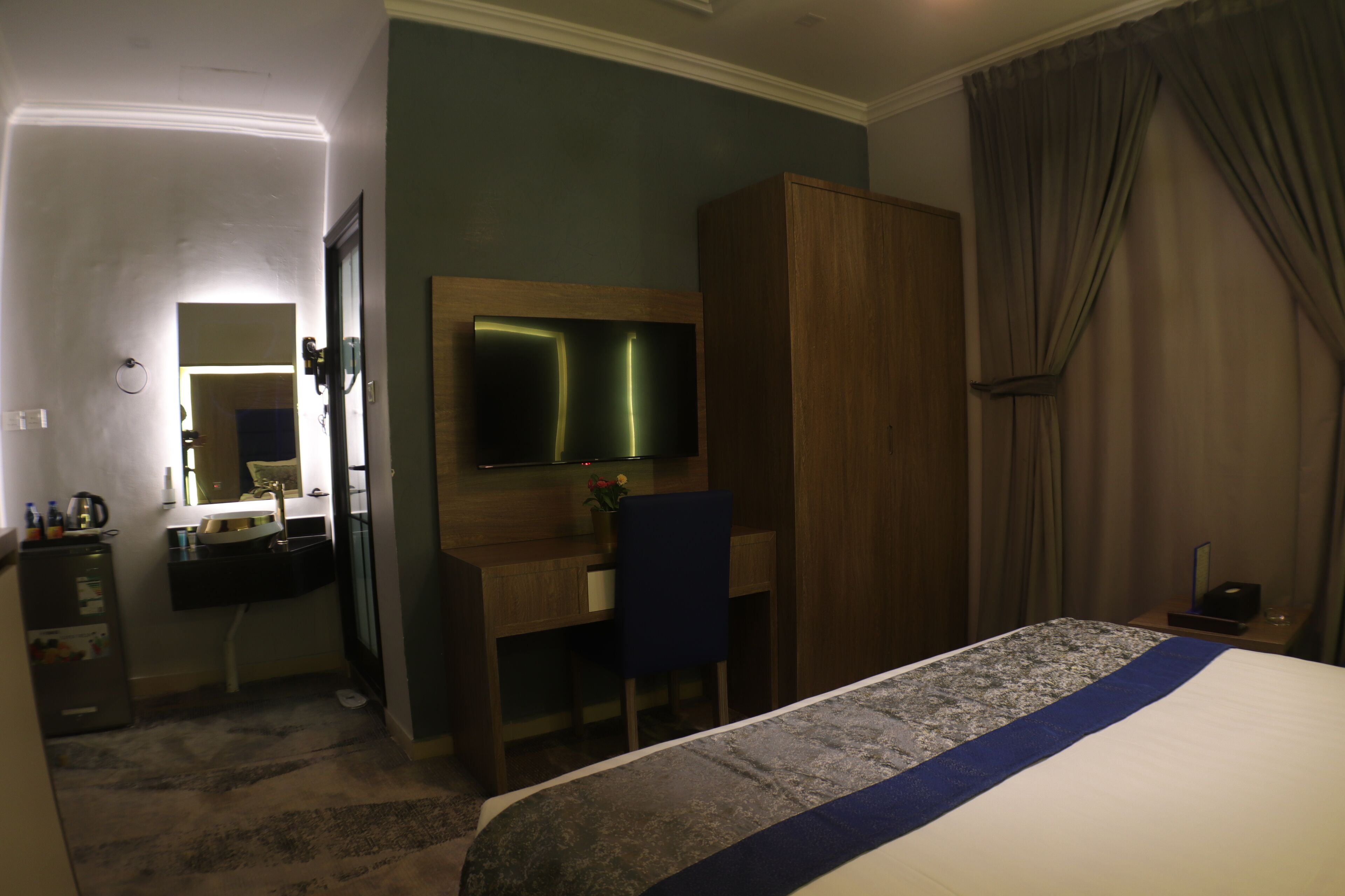 Une chambre d’hôtel comprenant un lit, un bureau avec une chaise, un miroir et une armoire.