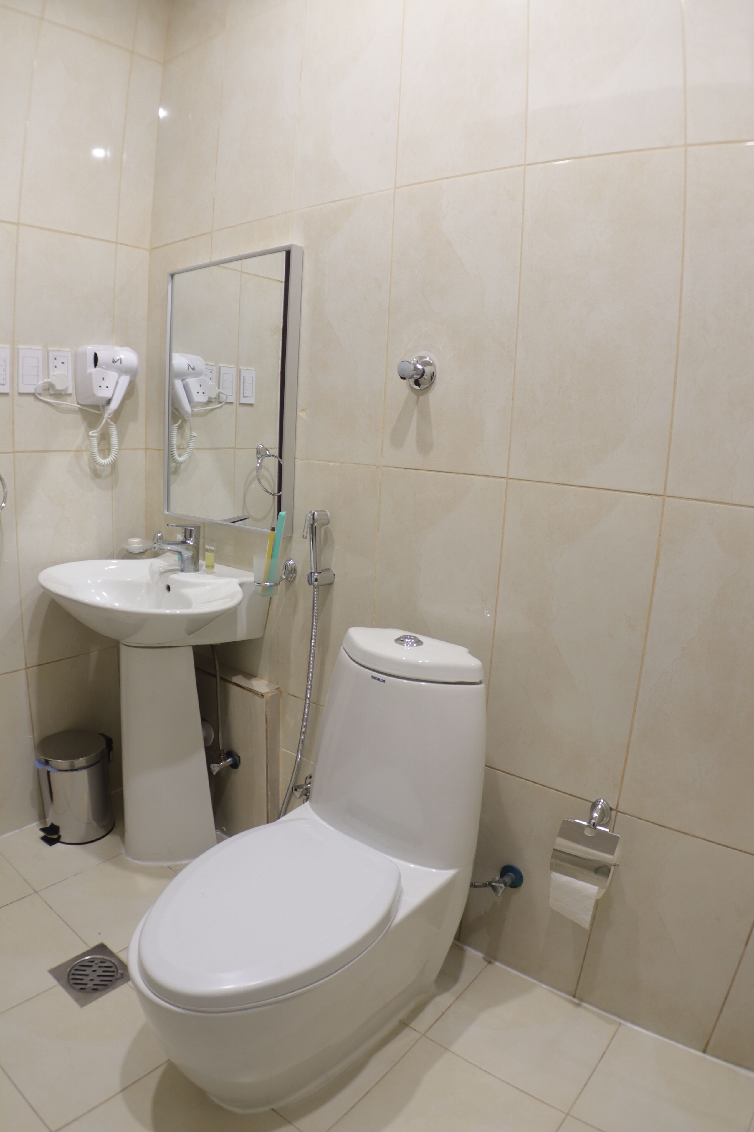 Een badkamer met toilet, wastafel en spiegel.