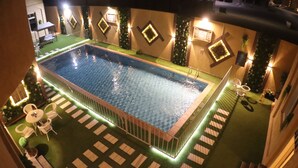 A rectangular pool with a tiled deck surrounding it, equipped with a ladder.