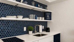 Eine moderne Küche mit schwarzem und weißem, sechseckigem Fliesenspiegel, weißen Schränken, einer Edelstahl-Spüle und einem Toaster auf der Arbeitsplatte.