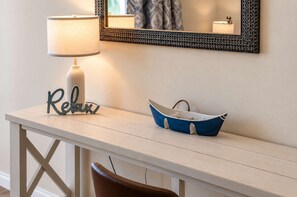 A white console table with a lamp, a decorative word 'Relax,' and a blue boat-shaped container.