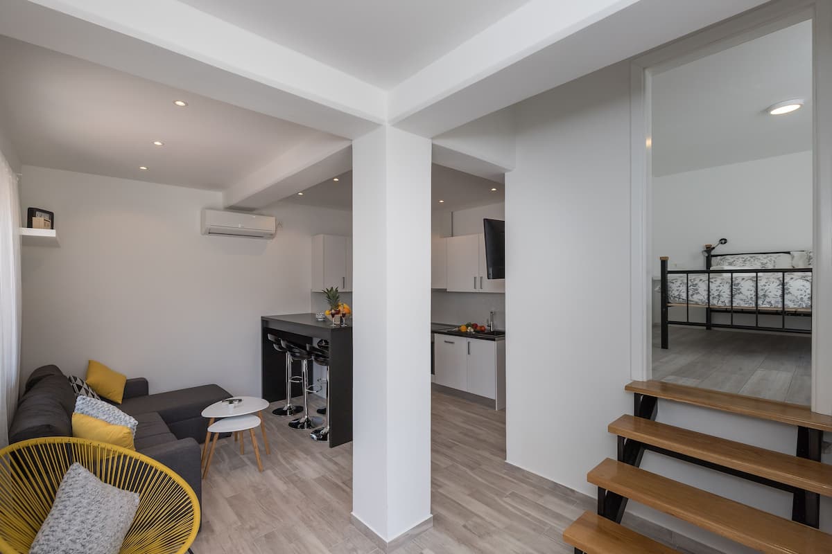 A modern apartment with a living area, kitchen, and a staircase.