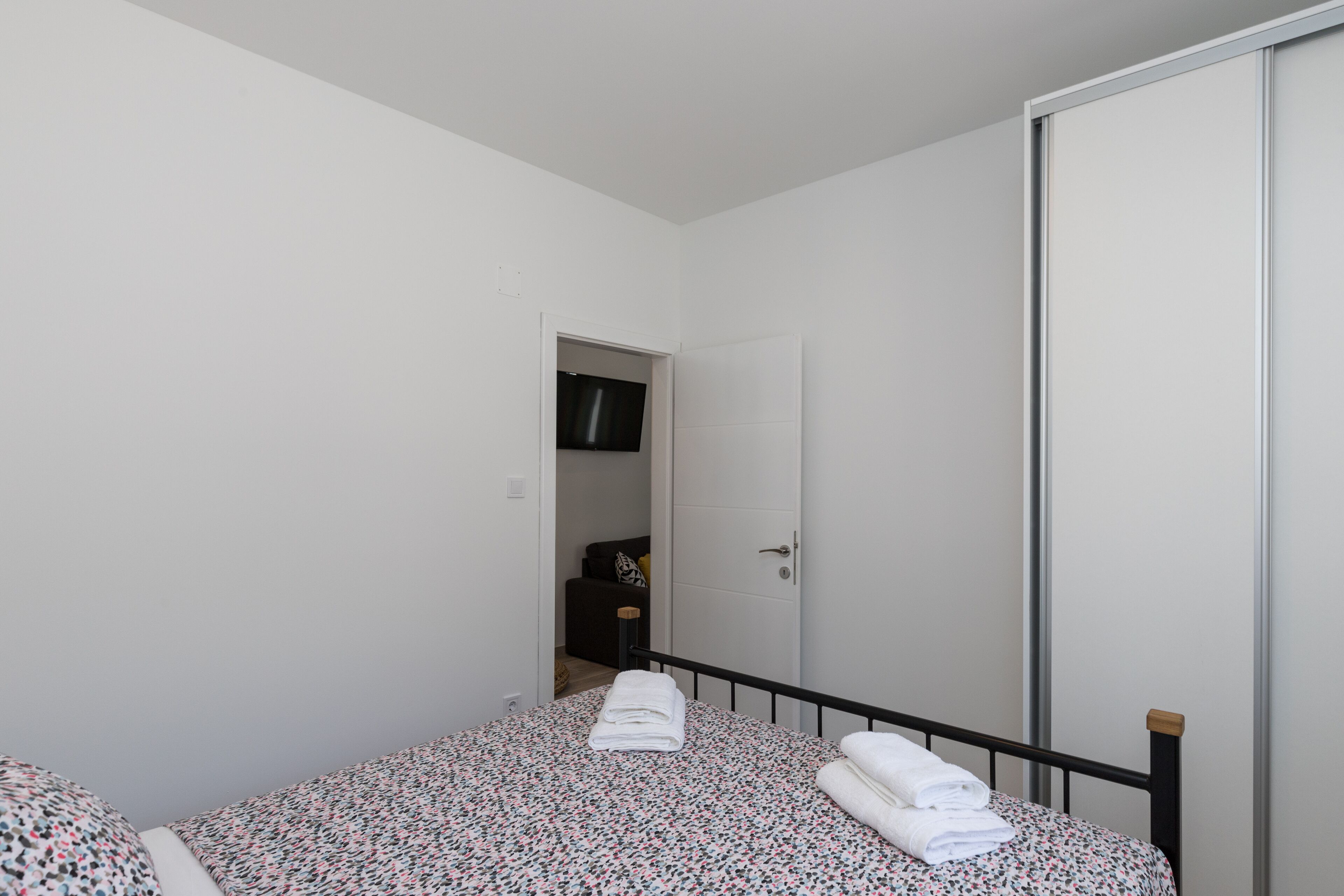 Ein Schlafzimmer mit einem Bett, einem Kleiderschrank und einer Tür zu einem anderen Raum.