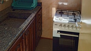 A kitchen with wooden cabinets, a gas stove, a window, and a dish rack. - Vers Les Nuages, Old Souk, Sea View Flat & Balcony (Batroun)