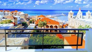 A coastal cityscape with a clear view of the sea, buildings with red-tiled roofs, and a prominent white church with a dome. - Vers Les Nuages, Old Souk, Sea View Flat & Balcony (Batroun)