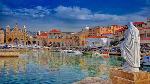A harbor with boats, a statue, and historic buildings with red roofs. - Vers Les Nuages, Old Souk, Sea View Flat & Balcony (Batroun)