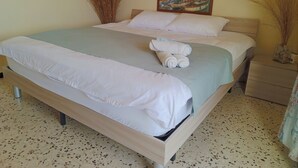 A double bed with white linens, a painting of a coastal town, and two tall dried plants beside the bed. - Vers Les Nuages, Old Souk, Sea View Flat & Balcony (Batroun)