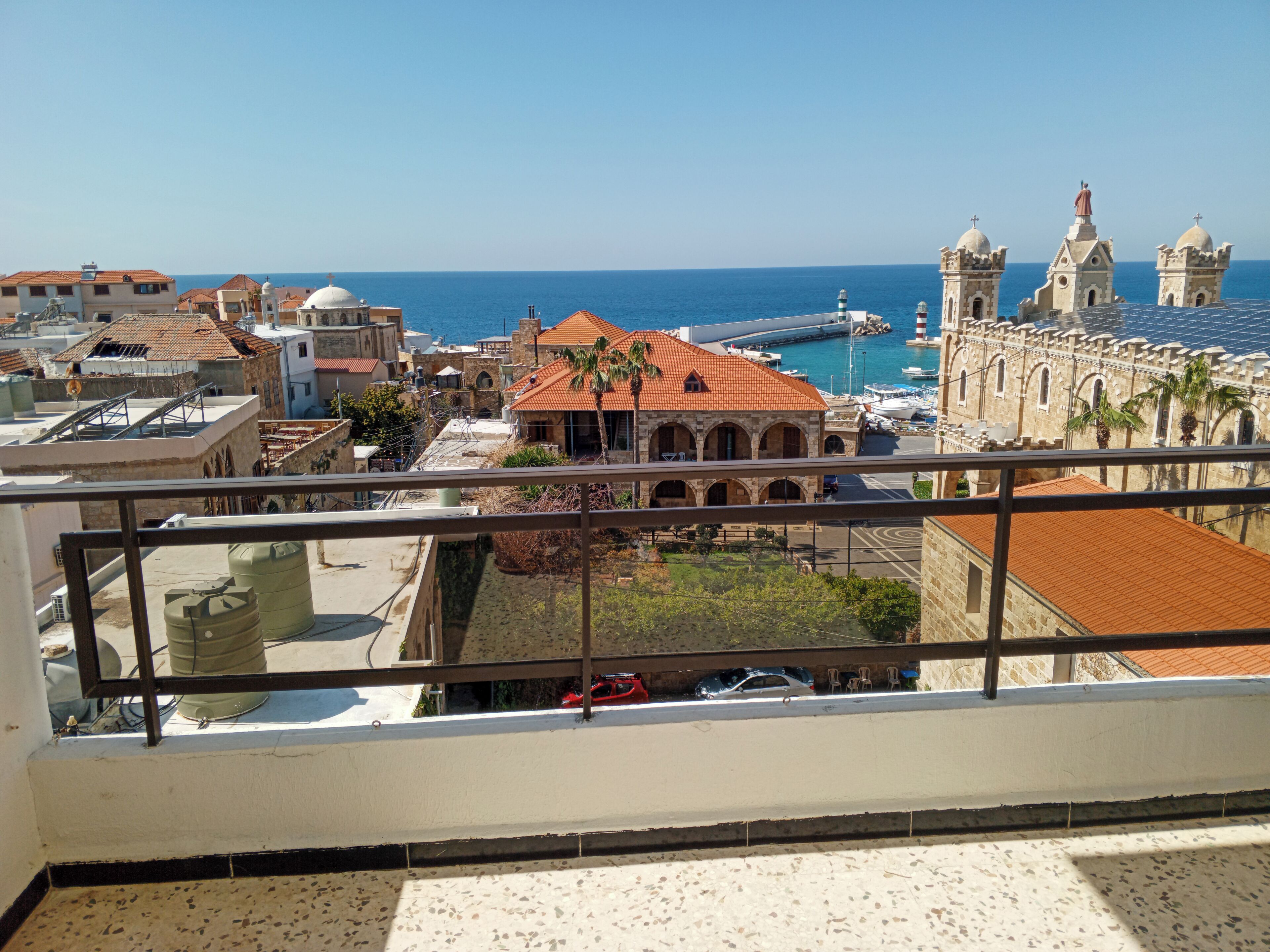 A balcony with a view of a coastal cityscape, including buildings and a marina.