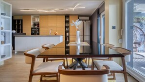 Uma sala de jantar moderna com uma mesa de vidro, quatro cadeiras e um vaso central.