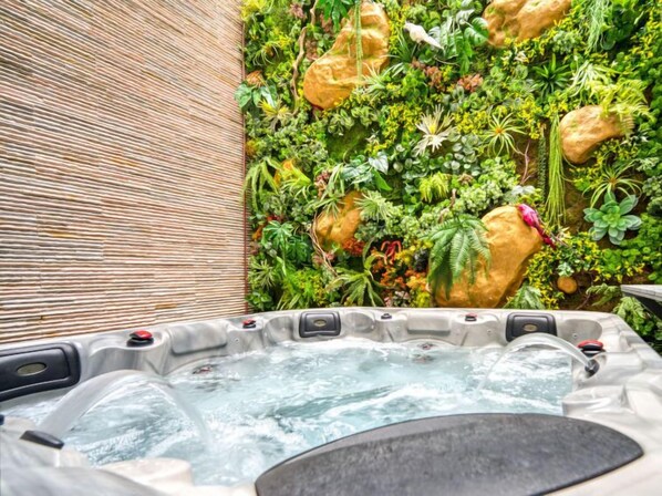 Un jacuzzi rodeado por una pared de plantas y rocas.