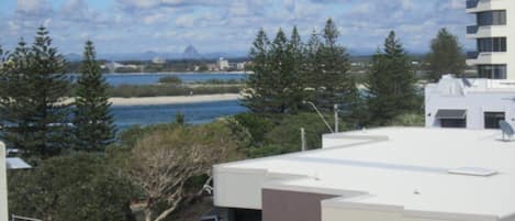 A residential area with a view of the sea, trees, and a building with a flat roof.