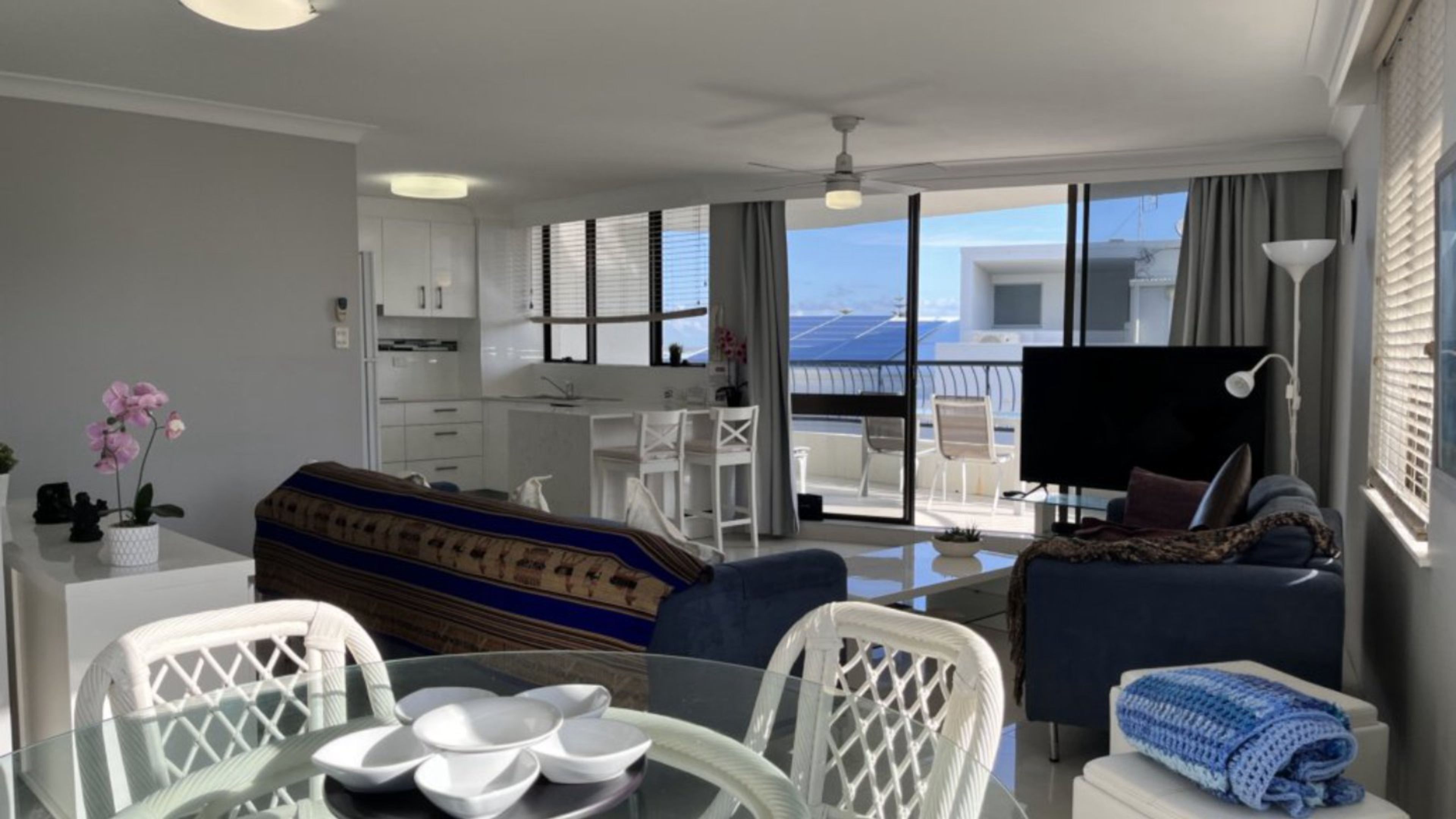 A modern hotel room with a balcony, a dining area, and a living space.