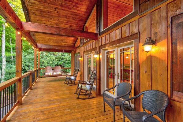 Relax on the deck with rocking chairs and a bench, surrounded by lush greenery and natural beauty.