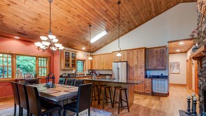 Una cocina amplia con armarios de madera, una isla grande con taburetes y un comedor con sillas.