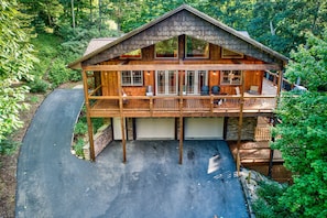 A two-story log cabin with a covered deck and a garage.