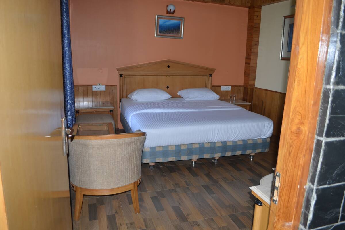 Ein Schlafzimmer mit einem Bett, einem Sessel, einem Nachttisch und einem Wandbild.