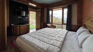 Une chambre avec un grand lit, une télévision, un bureau et une vue sur l’extérieur.