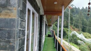 Un couloir aux murs de pierre, au plafond en bois et au sol recouvert d’un tapis de gazon synthétique vert.