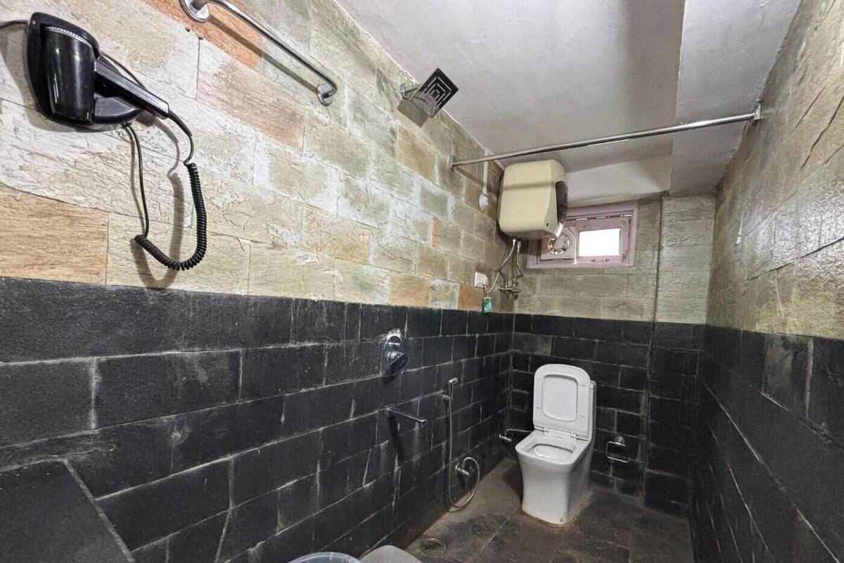 Ein Badezimmer mit Toilette, einem Händetrockner und einem Mülleimer.
