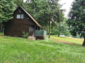 A rustic wooden cabin with a steeply pitched roof, surrounded by lush greenery and trees. - An idyllic vacation home surrounded by nature (Neunkirchen)