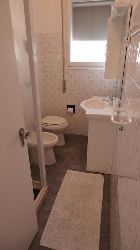 A small bathroom with a toilet, sink, and a window above the sink.