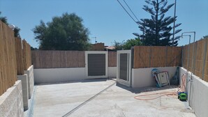 Une terrasse sur le toit avec un sol en béton, une clôture en bois et un portail en métal.