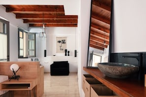 A modern kitchen with wooden beams, a large mirror, and a stone sink.