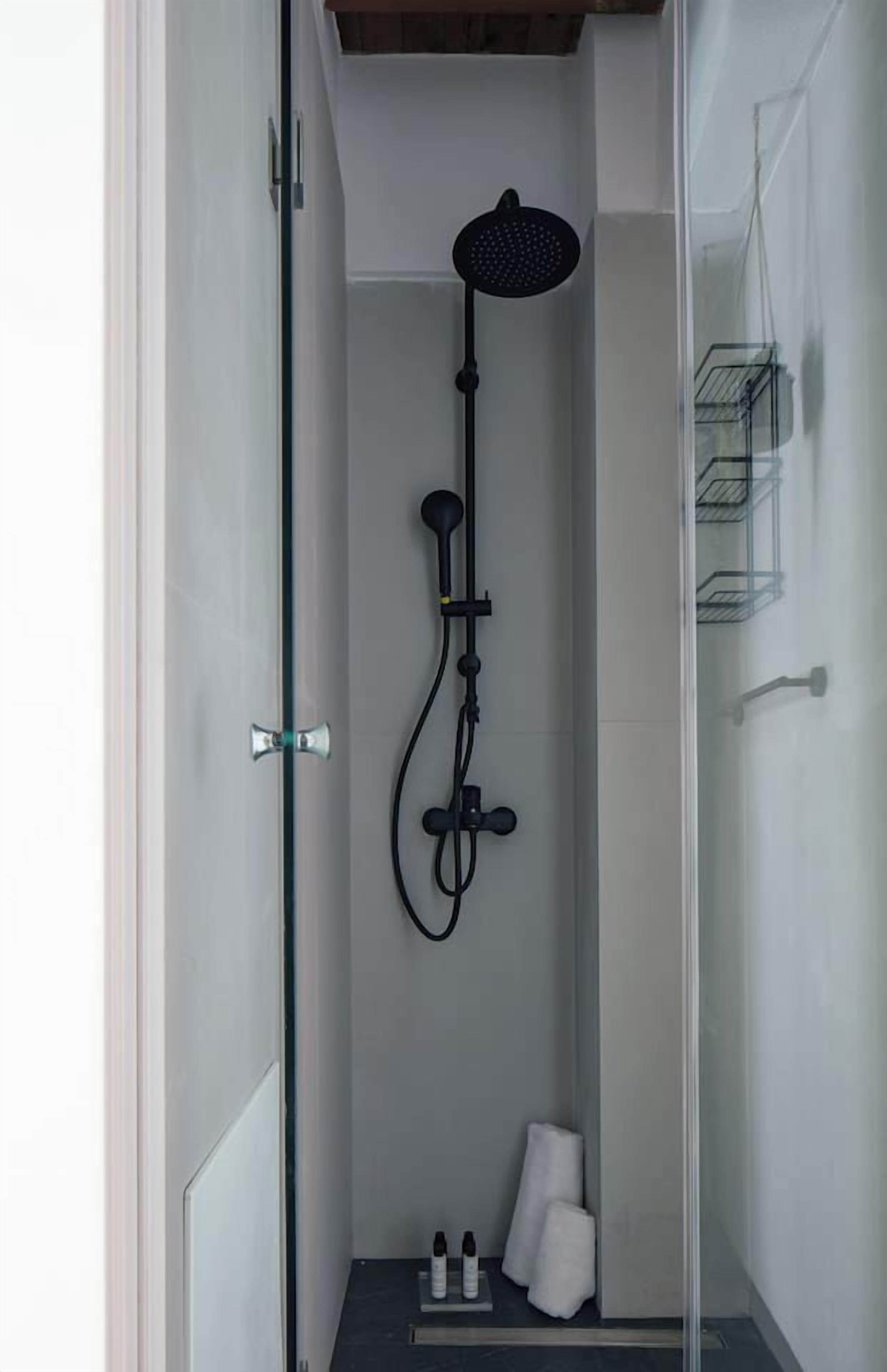 Eine begehbare, gläserne Dusche mit Handbrause und Wandarmatur.