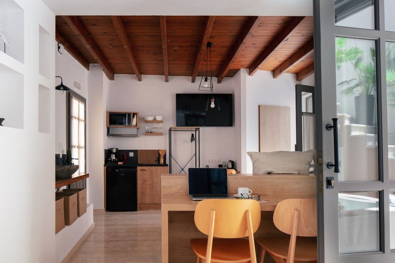 Un espace de vie compact comprenant un coin cuisine, un coin repas et un lit.