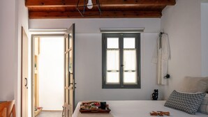 Un dormitorio con cama, ventana, puerta y una pequeña mesa con comida.