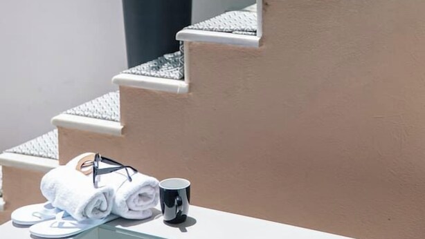 Un baño con bañera, un perchero con toallas y chanclas, y dos plantas en macetas sobre una escalera.