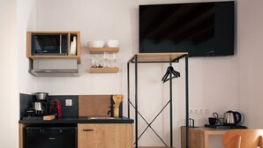 Una cocina compacta con microondas, lavamanos y una cafetera negra.