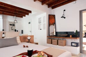 A modern bedroom with a large bed, bedside tables, a mirror, and a built-in shelf with a plant. - Gateway Suites - Harmony (Ρέθυμνο)