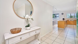 Une cuisine moderne avec un îlot central en bois, des meubles blancs et un grand miroir au-dessus du plan de travail.